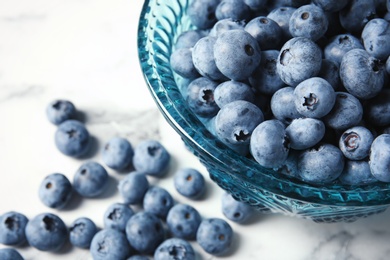 Photo of Bowl with fresh blueberries on marble table, closeup