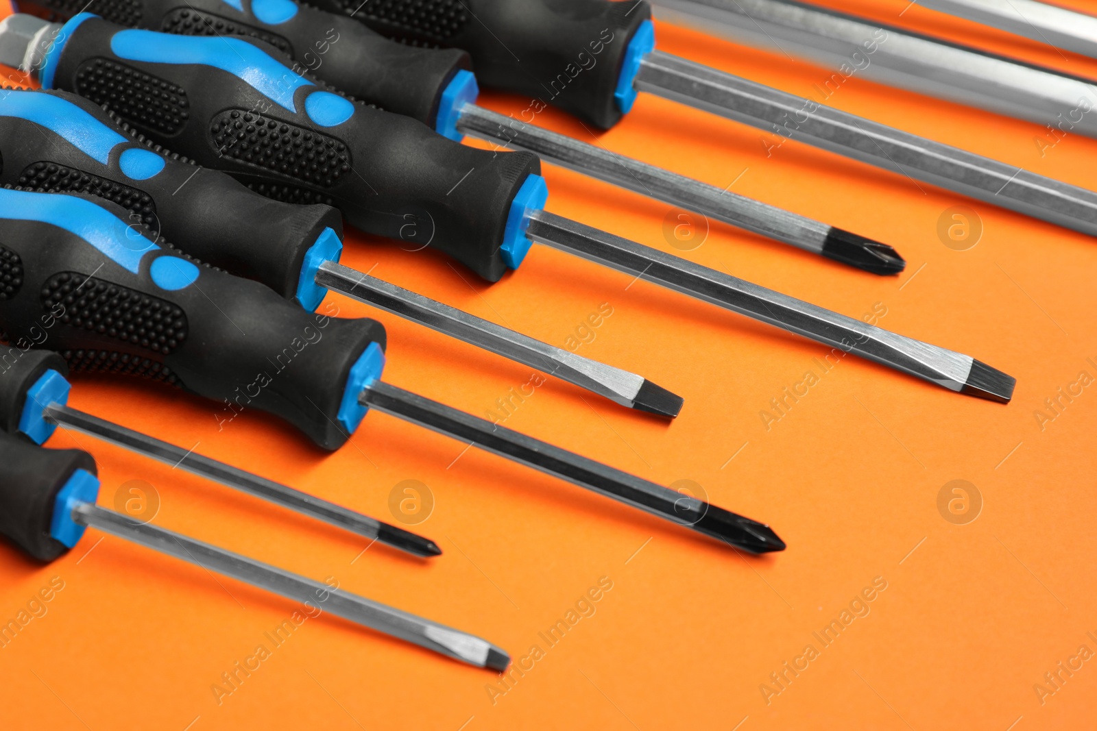 Photo of Set of screwdrivers on orange background, closeup