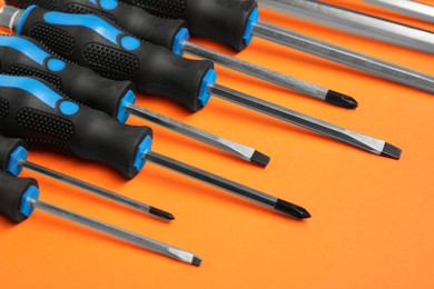 Photo of Set of screwdrivers on orange background, closeup