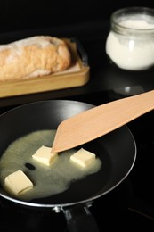 Photo of Stirring melting butter in frying pan at table, closeup