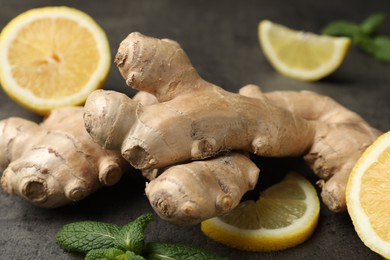 Photo of Fresh lemon, ginger and mint on grey table, closeup