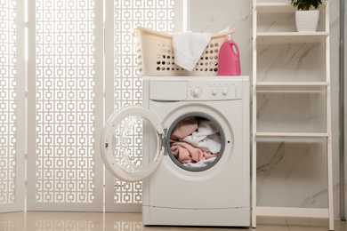 Photo of Modern washing machine with towels in bathroom