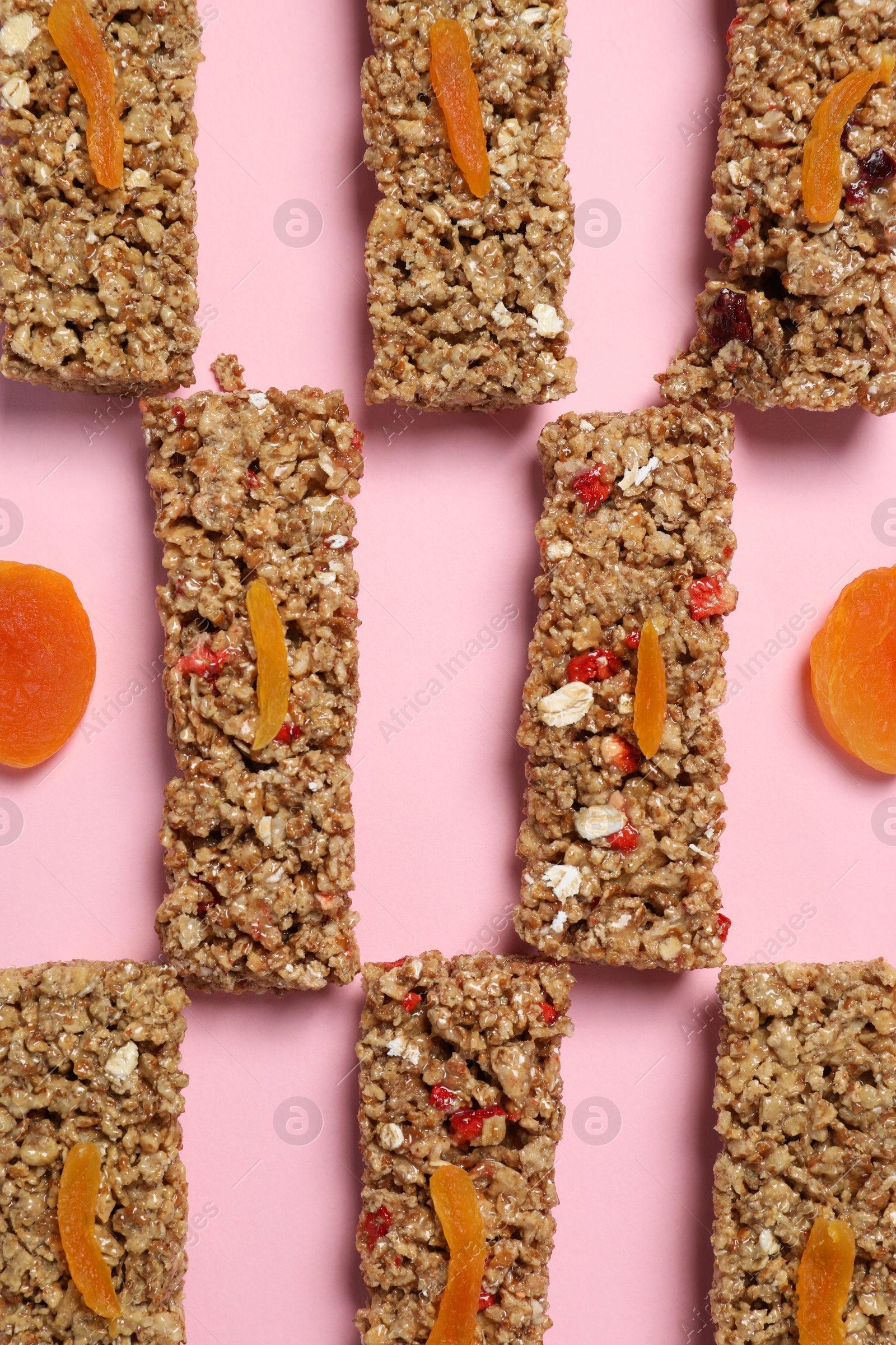 Photo of Tasty granola bars on pink background, flat lay