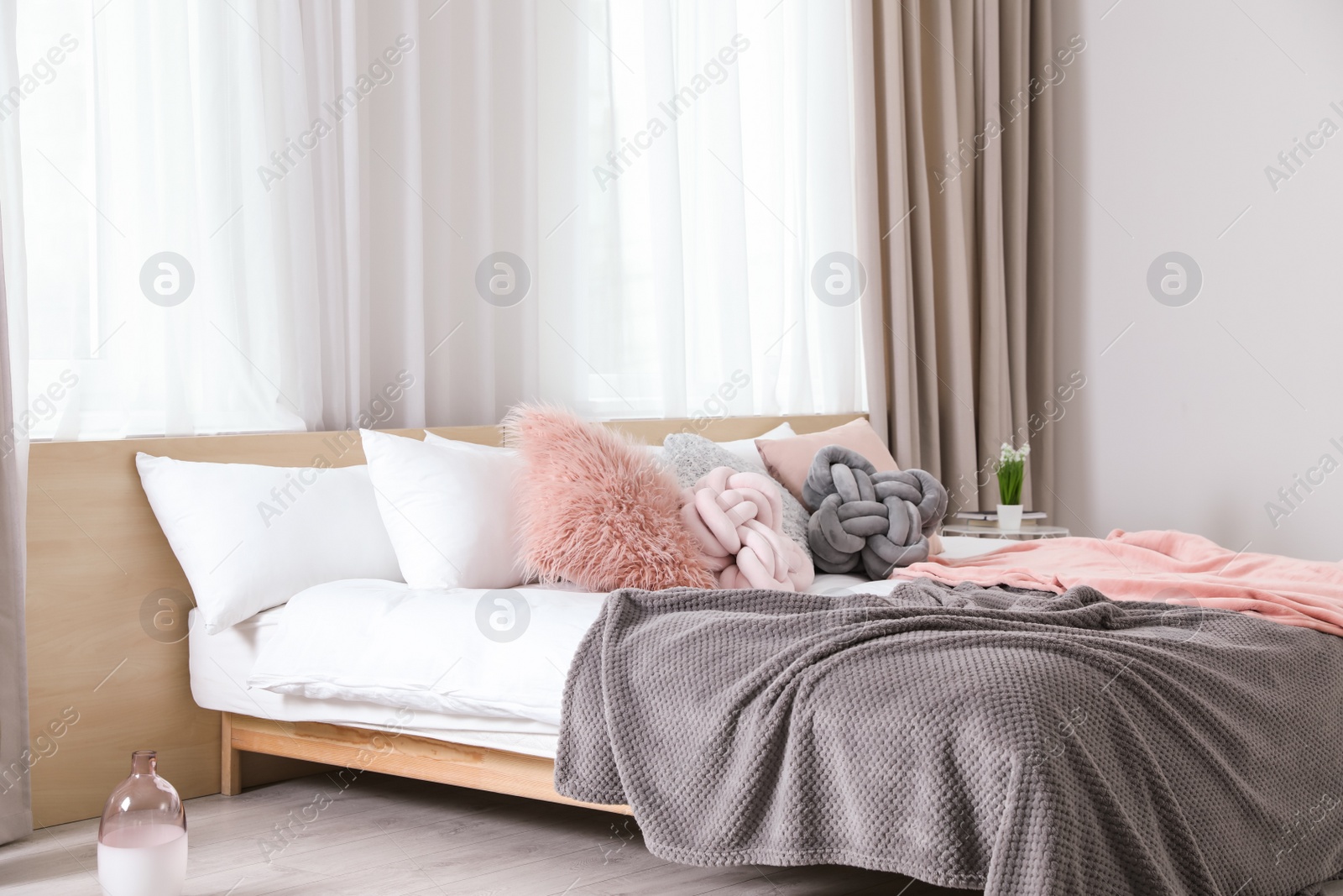 Photo of Comfortable bed with pillows and plaid in modern room interior