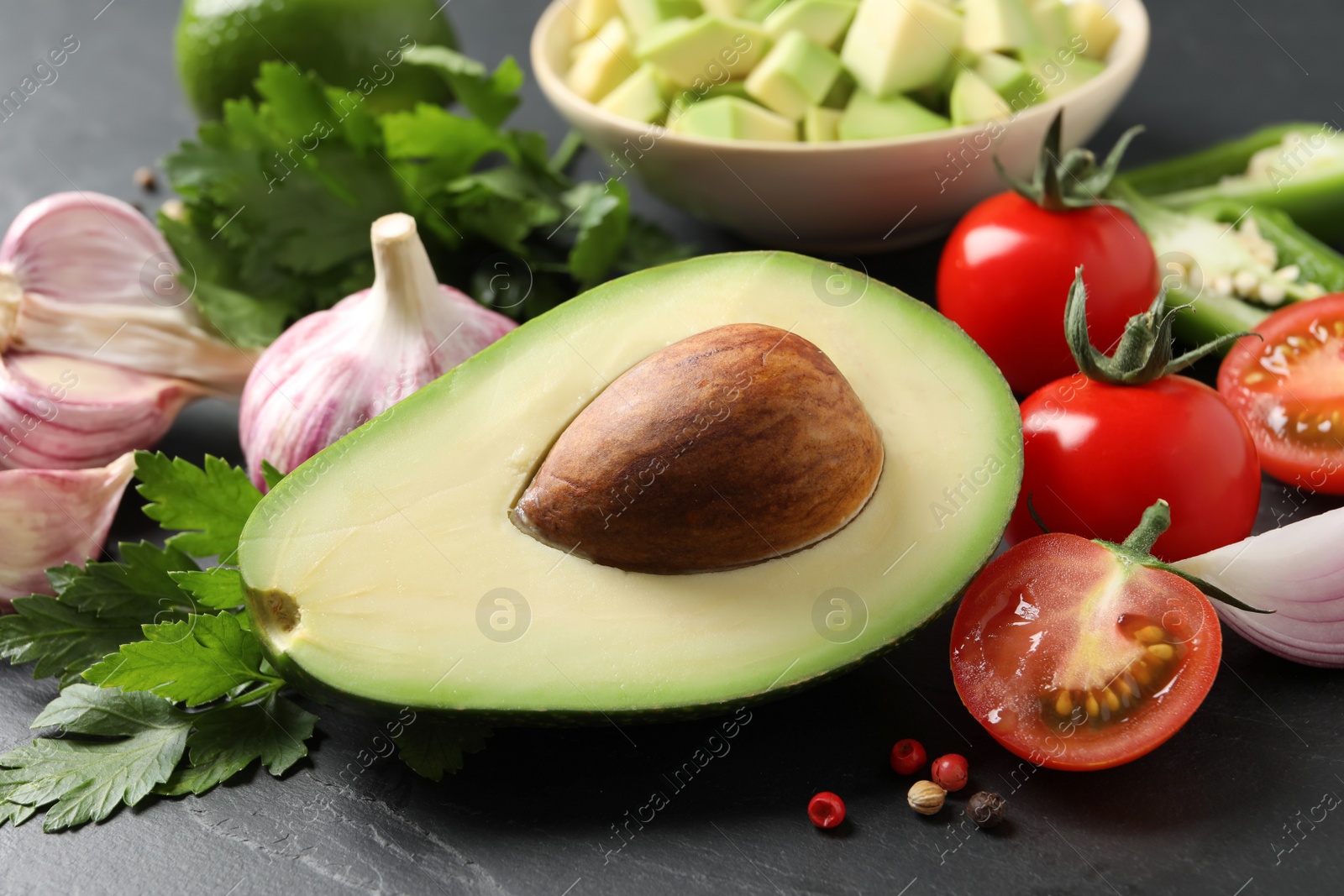 Photo of Fresh ingredients for guacamole on black table, closeup