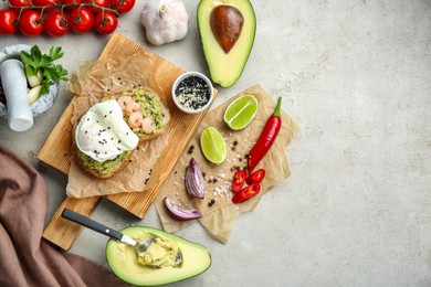 Delicious sandwich with guacamole, shrimps, fried egg and ingredients on light grey table, flat lay. Space for text