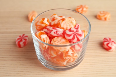 Photo of Glass with delicious colorful candies on wooden table