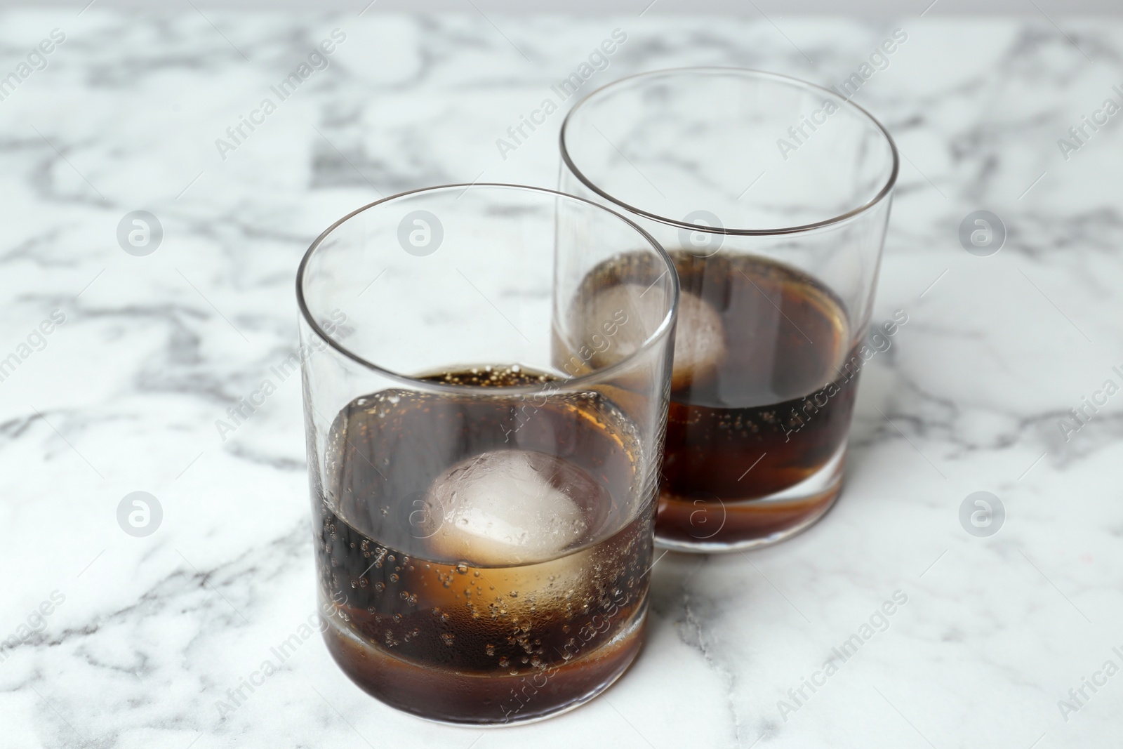 Photo of Cocktails with ice balls on white marble table