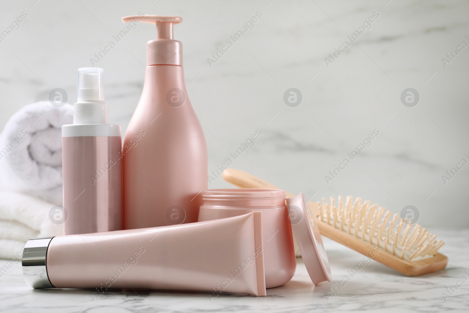 Photo of Set of hair cosmetic products and brush on white marble table