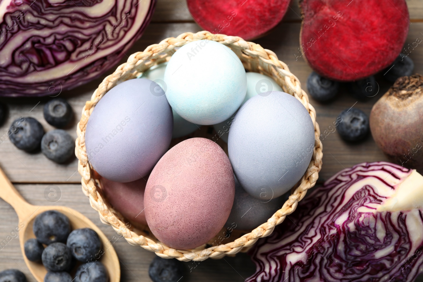 Photo of Colorful Easter eggs painted with natural dyes and ingredients on wooden table, above view