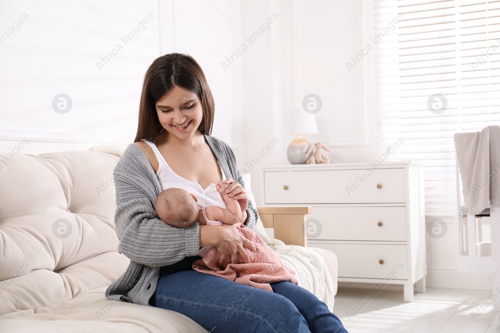 Photo of Young woman breastfeeding her little baby at home