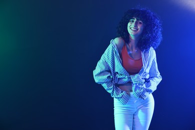 Photo of Beautiful young woman posing on color background in neon lights. Space for text