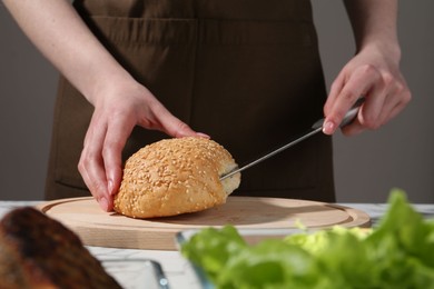 Photo of Woman making delicious vegetarian burger at table, closeup