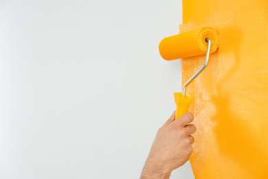 Photo of Man painting white wall with yellow dye, closeup. Interior renovation