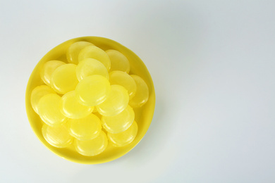 Photo of Tasty small lemon drops on white background, top view