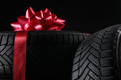 Photo of Winter tires with red ribbon on black background, closeup