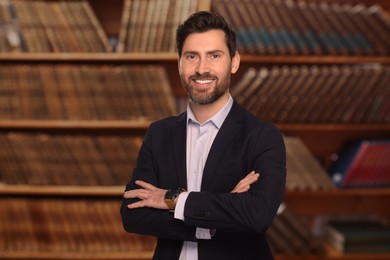 Successful lawyer smiling against shelves with books