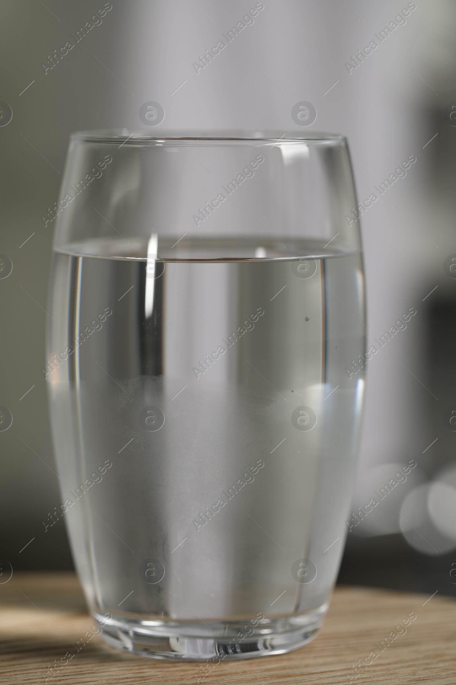 Photo of Glass of pure water on wooden table against blurred background, closeup