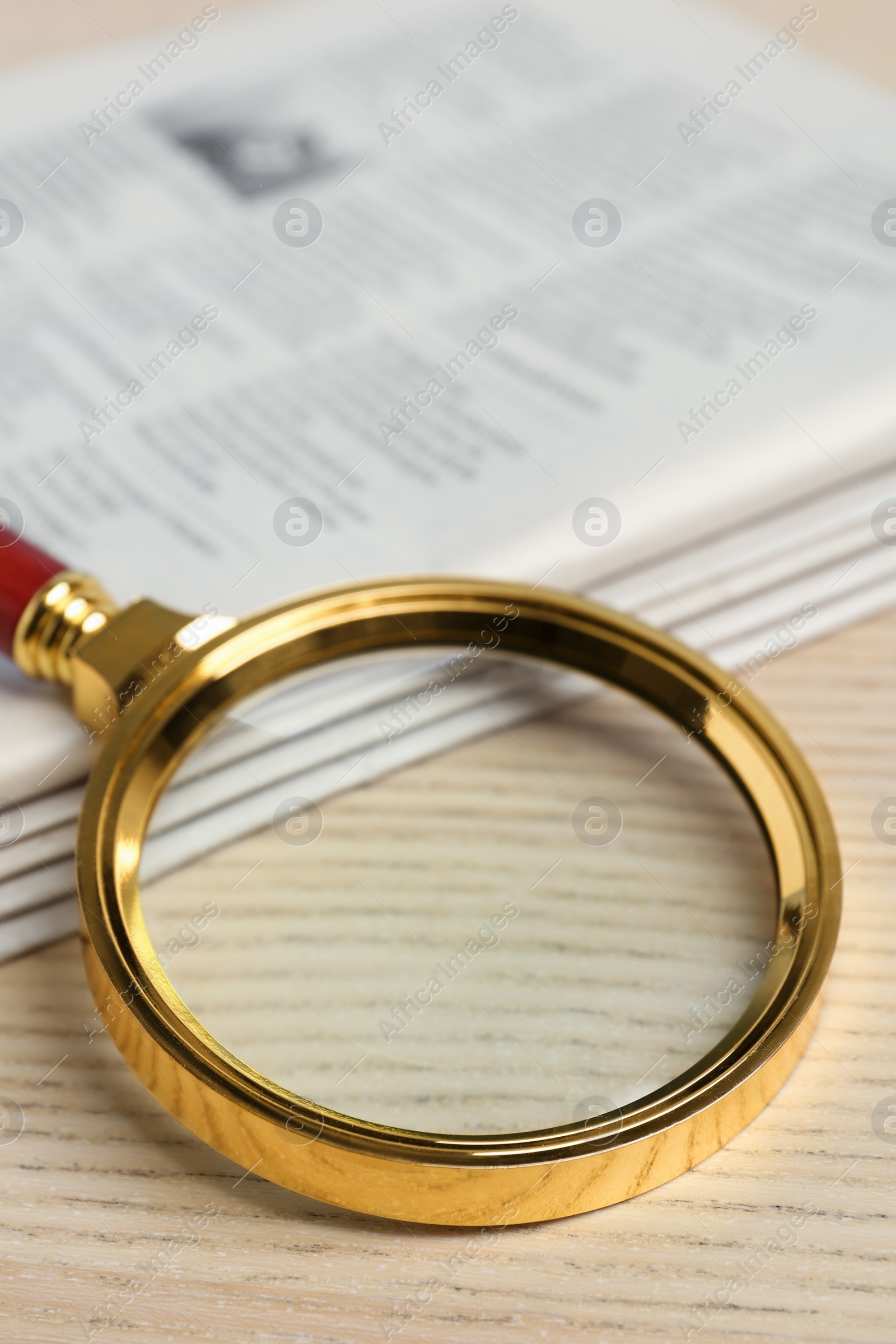 Photo of Stack of newspapers and magnifier on wooden table. Search concept