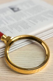 Stack of newspapers and magnifier on wooden table. Search concept