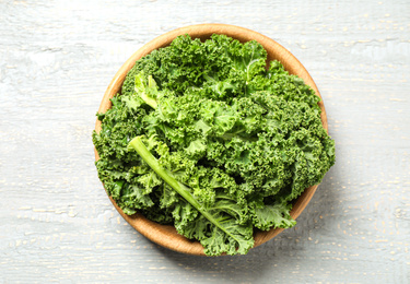 Photo of Fresh kale leaves on light grey wooden table, top view