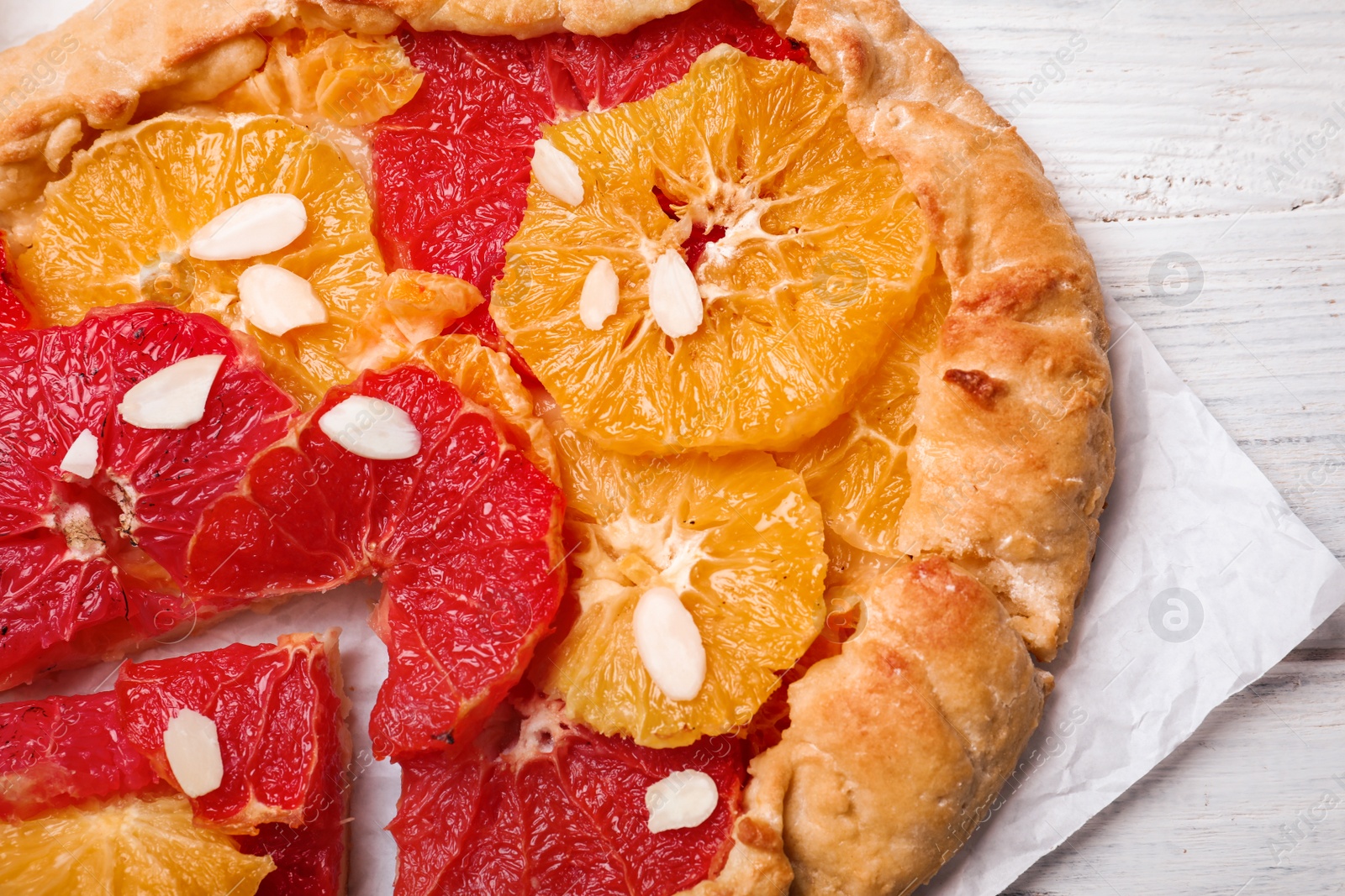 Photo of Tasty galette with citrus fruits on white table, top view