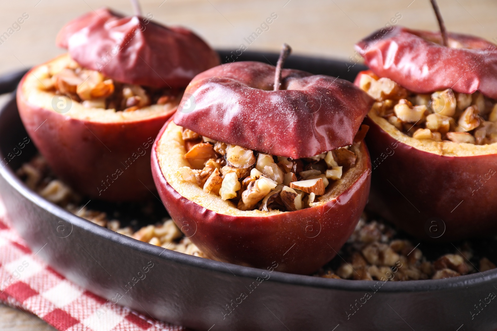 Photo of Tasty baked apples with nuts in baking dish on table, closeup