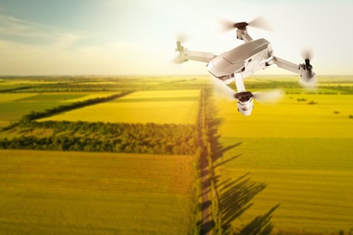Image of Modern drone flying over fields on sunny day. Aerial survey
