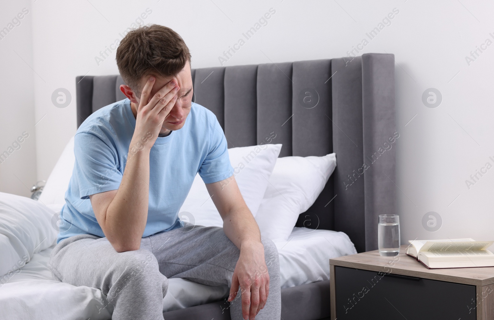 Photo of Sad man suffering from headache on bed indoors, space for text