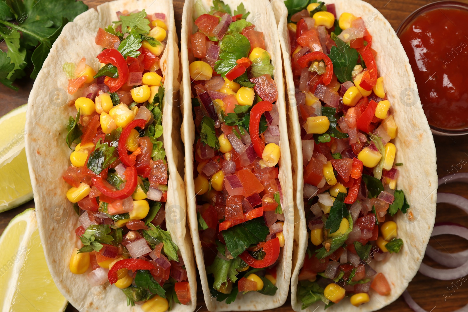 Photo of Tasty tacos with vegetables on wooden table, flat lay