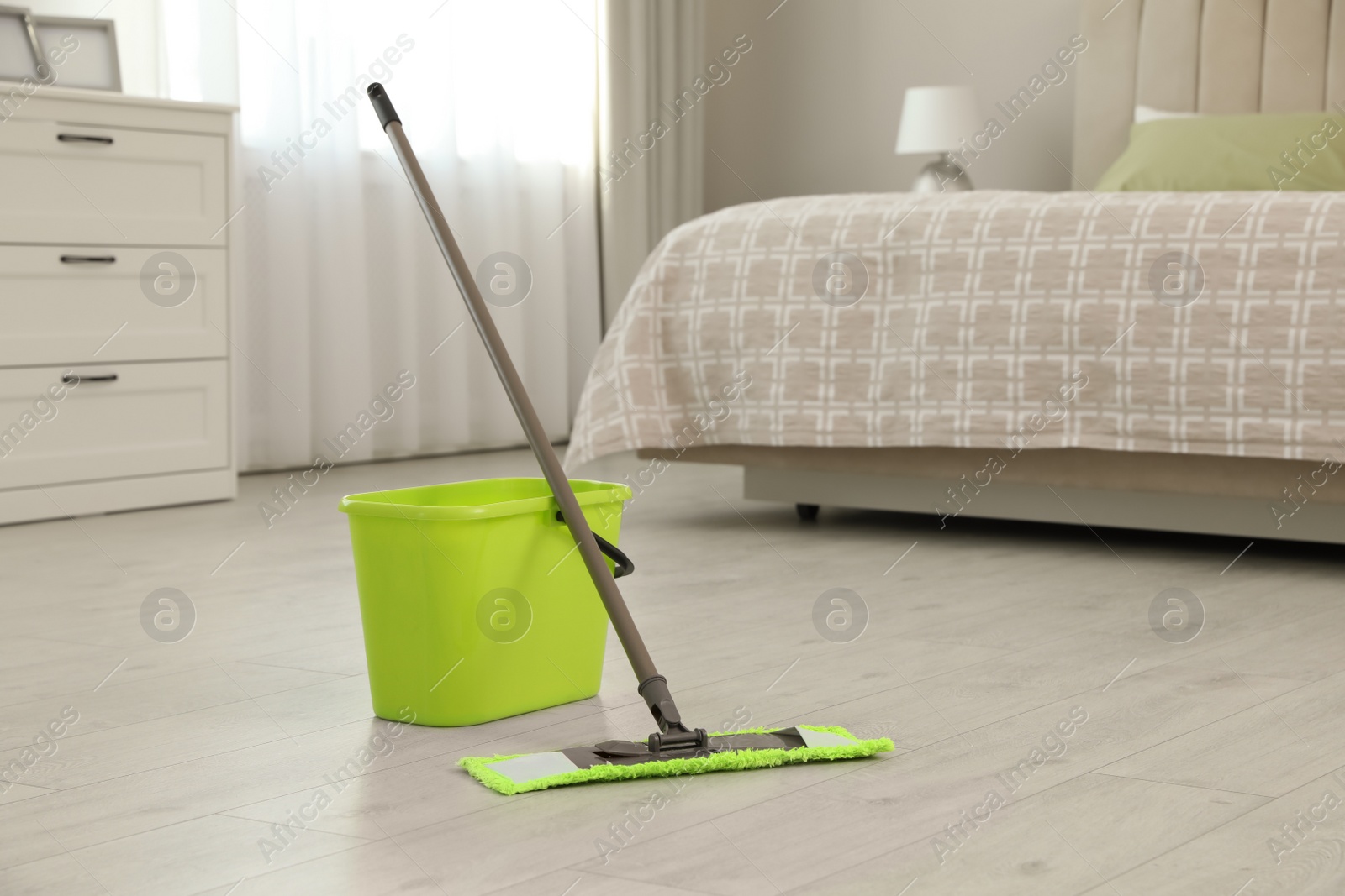 Photo of Bucket and mop on floor at home. Cleaning equipment
