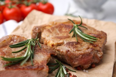 Photo of Delicious fried meat with rosemary on parchment paper, closeup