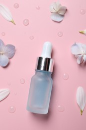 Bottle of cosmetic serum and beautiful flowers on pink background, flat lay