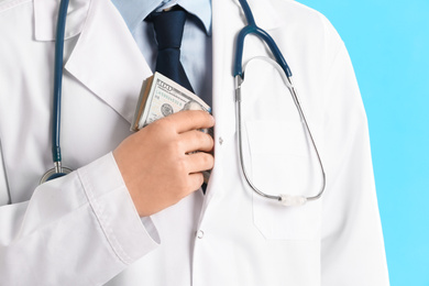 Photo of Doctor putting bribe into pocket on light blue background, closeup. Corruption in medicine
