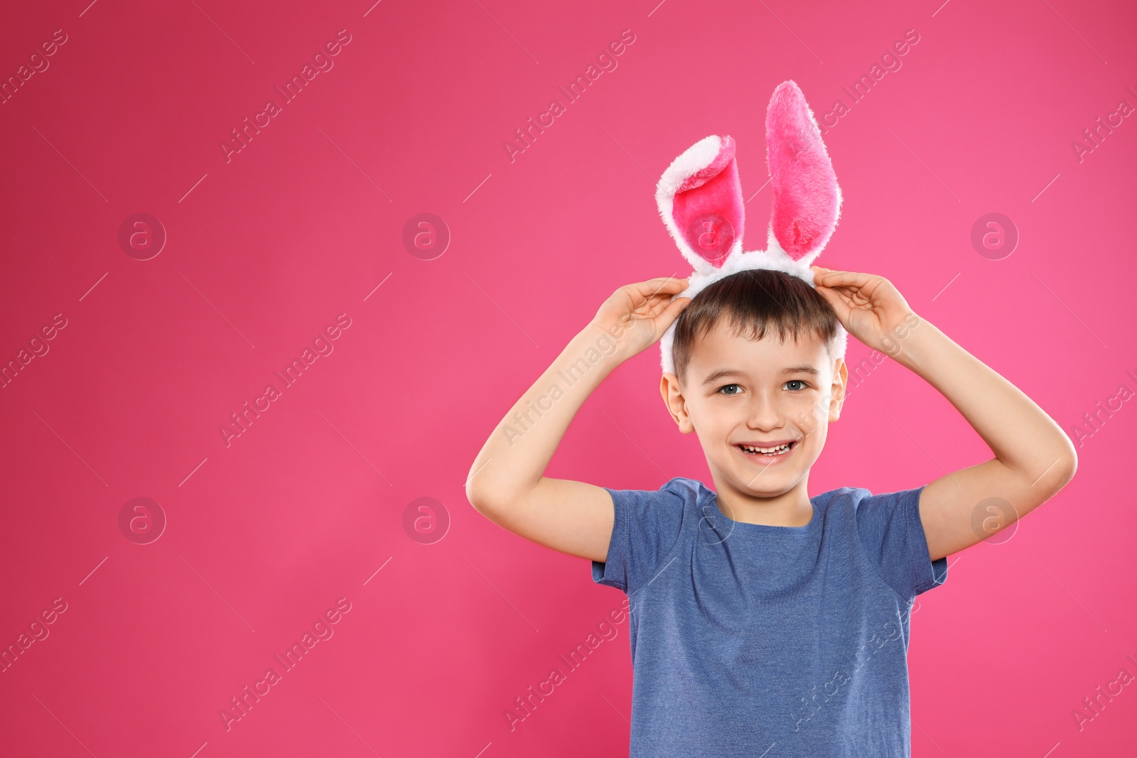 Photo of Portrait of little boy in Easter bunny ears headband on color background, space for text