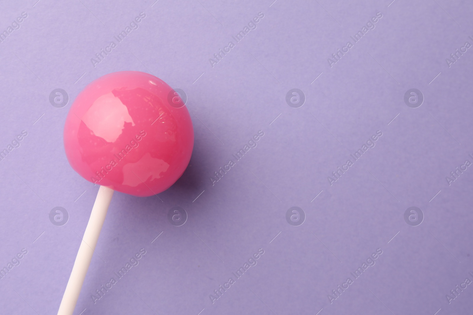 Photo of Tasty lollipop on violet background, top view. Space for text