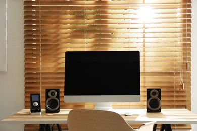 Photo of Modern computer with audio speakers and remote on table indoors