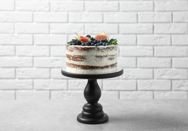 Delicious homemade cake with fresh berries on table near brick wall