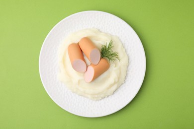 Photo of Delicious boiled sausages, mashed potato and dill on green background, top view
