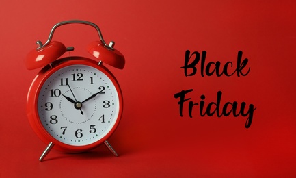 Photo of Phrase Black Friday and alarm clock on red background