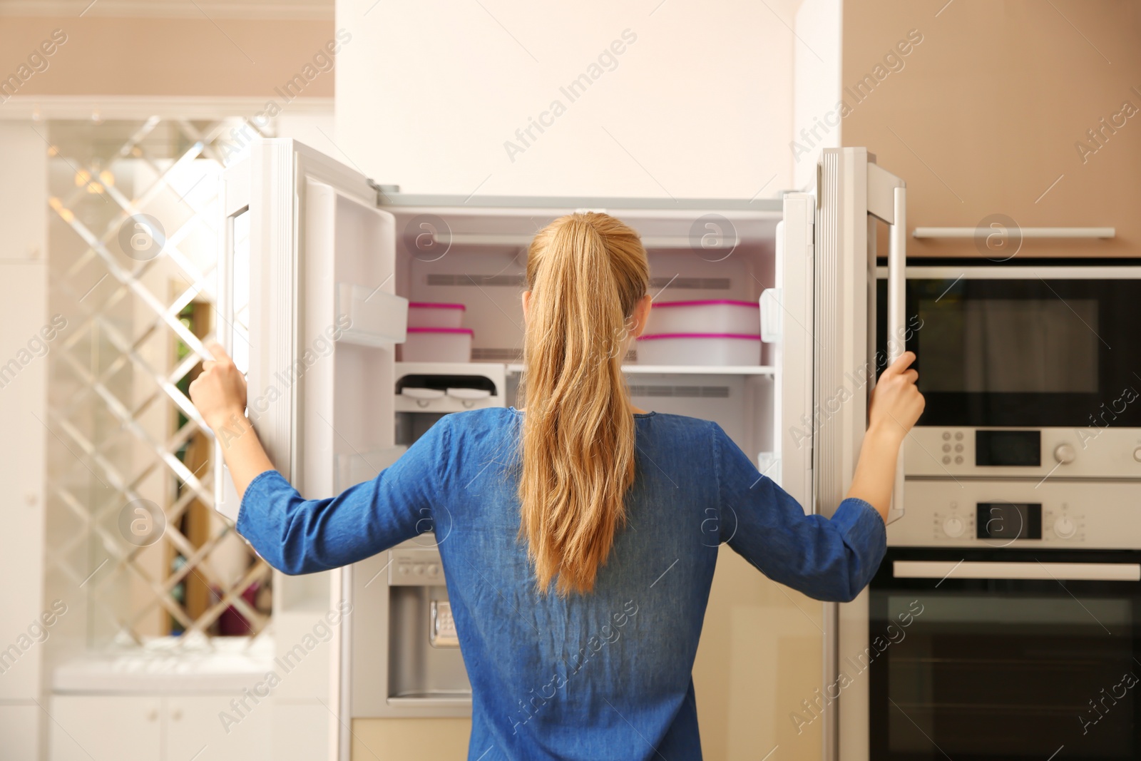 Photo of Young woman choosing food in refrigerator at home