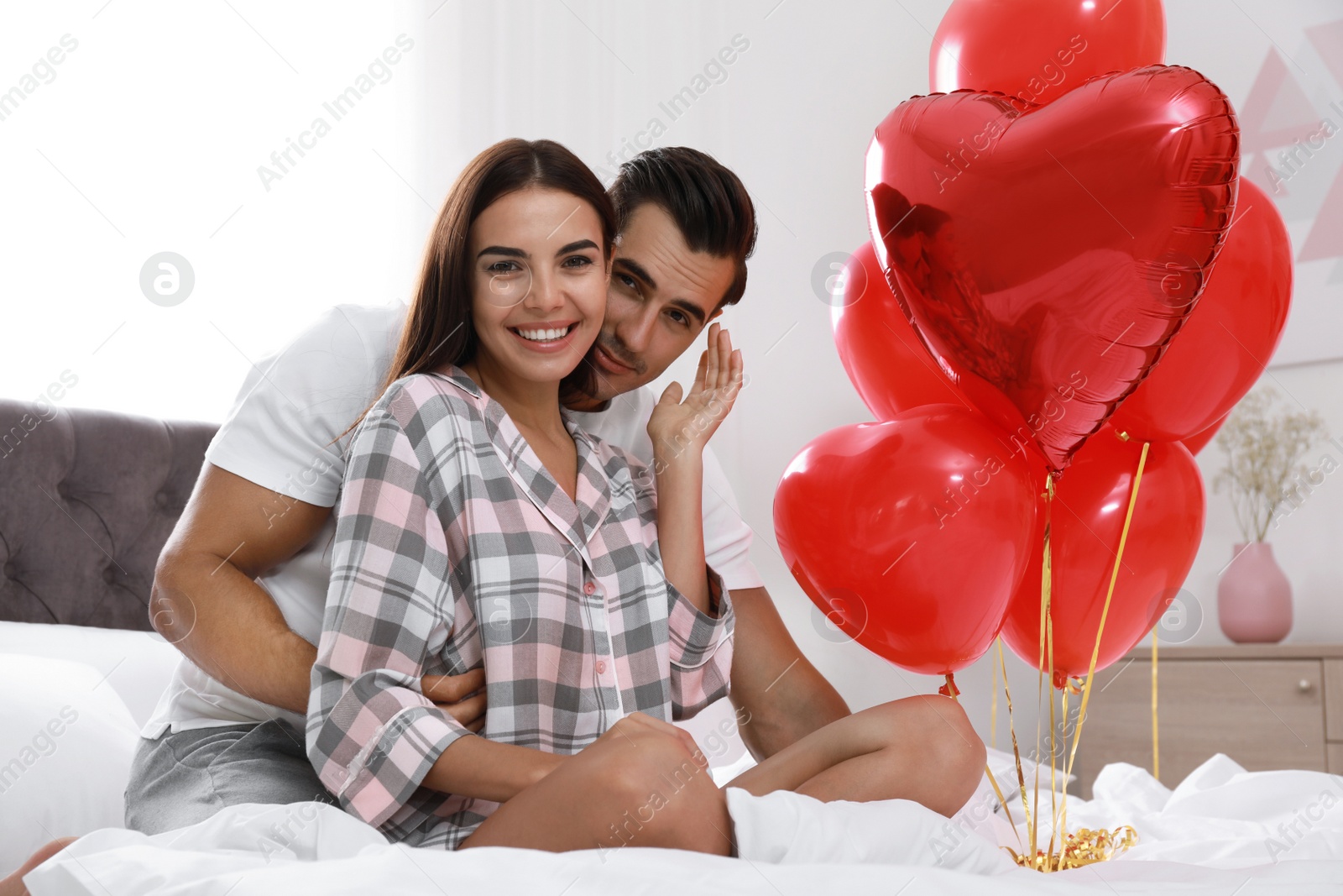 Photo of Beautiful couple with heart shaped balloons in bedroom