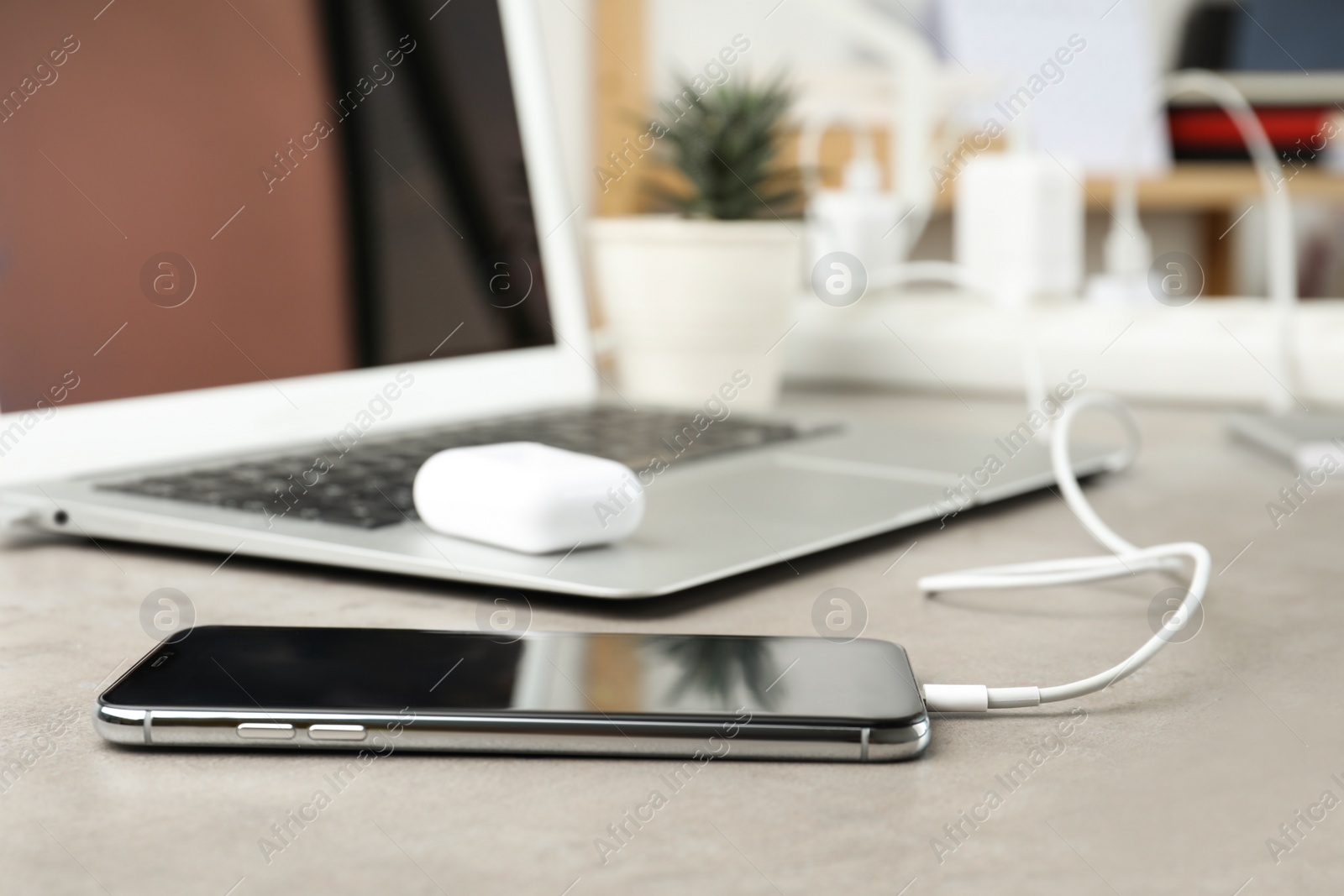 Photo of Smartphone charging with cable on light stone table