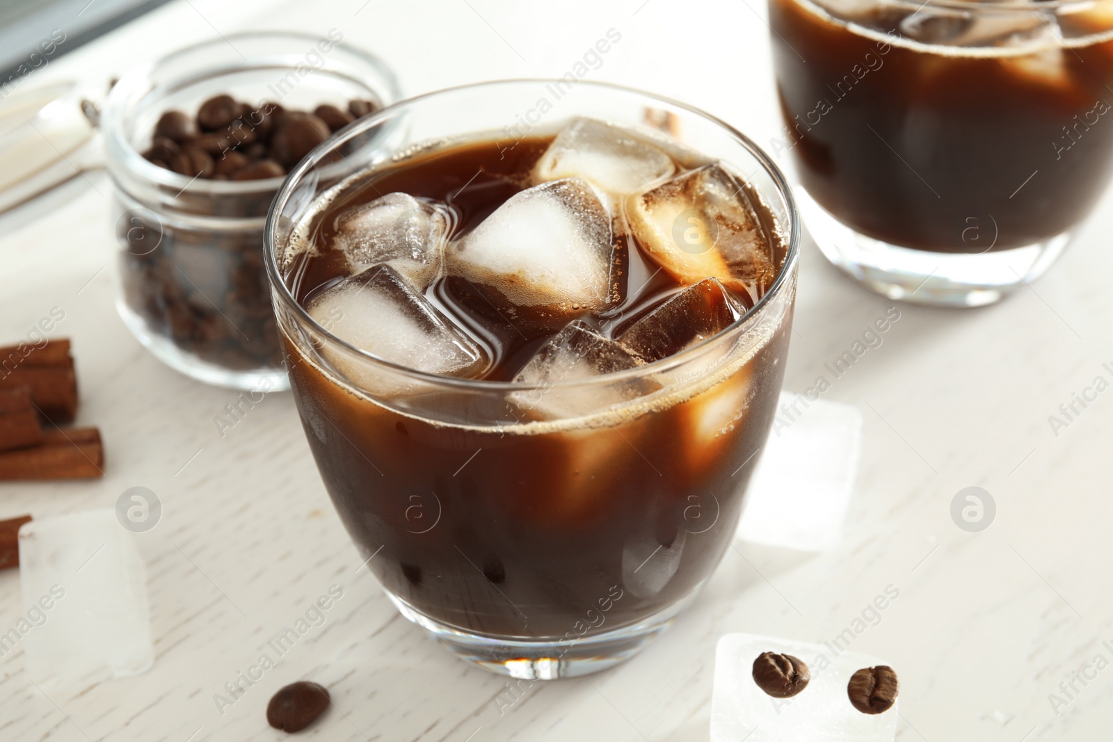 Photo of Glass of coffee drink with ice cubes on table