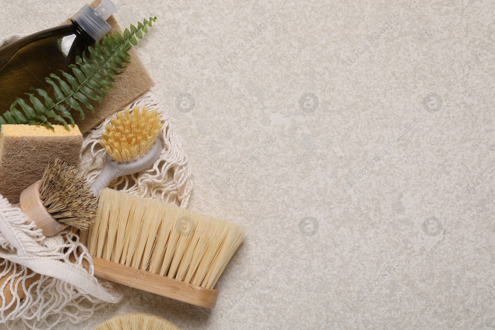 Photo of Different cleaning supplies in string bag on beige background, top view. Space for text