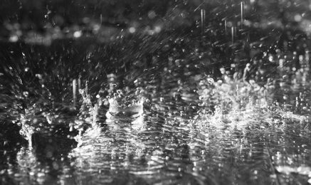 Photo of Heavy rain falling down on ground against dark background