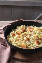 Delicious scallop pasta with onion in pan on table