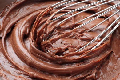 Photo of Whipping chocolate cream with balloon whisk, closeup view