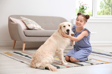 Photo of Cute little child with her pet on floor at home