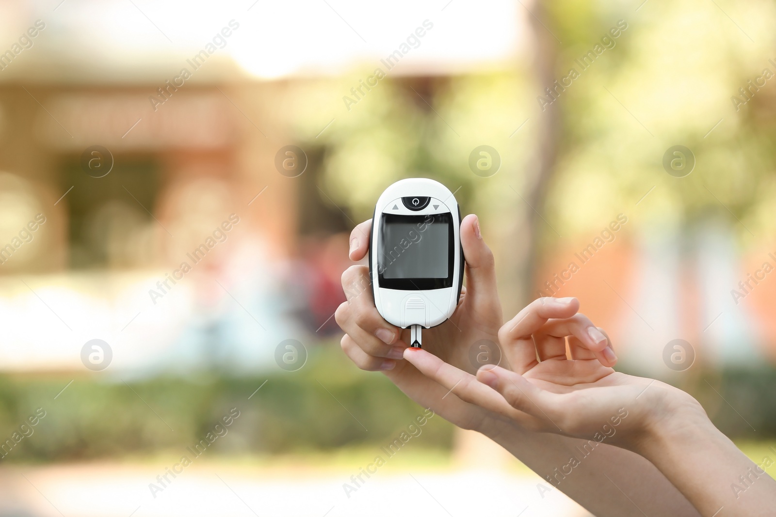 Photo of Woman using digital glucometer on blurred background. Diabetes control